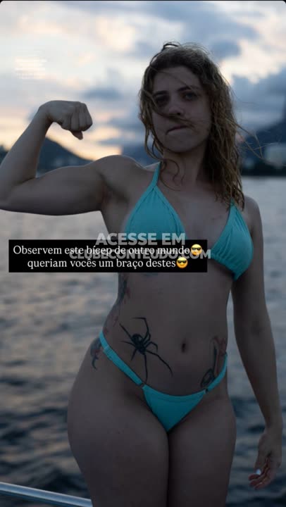 Loira de biquíni turquesa exibe bíceps de aço no mar